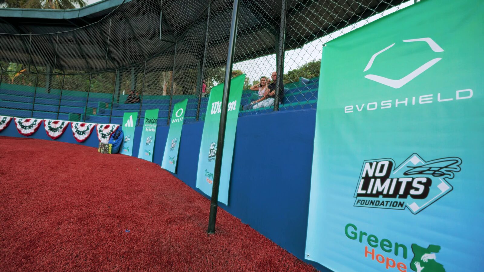 Campo de béisbol sintético de la Fundación No Limits — Pista de advertencia sintética roja junto a la pared del outfield